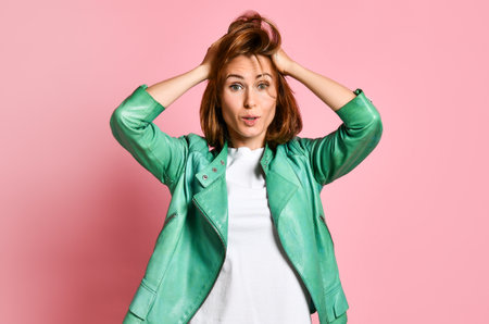 Portrait of a bewildered young woman clutching her head in amazement, does not know what to do nextの写真素材