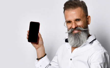 Hipster man with glasses shows the phone to the camera and confidently smiling.の写真素材