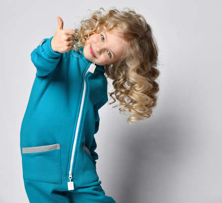 Happy smiling girl in jumpsuit showing thumbs upの写真素材