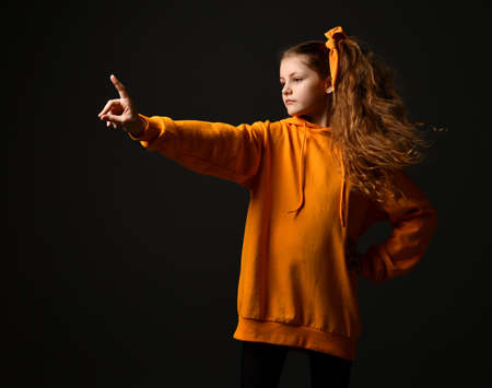 Candid and determined teen girl showing stop sign standing on black background.の写真素材