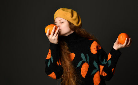 Girl holds oranges in her hands and sniffs them with her eyes closed.の写真素材