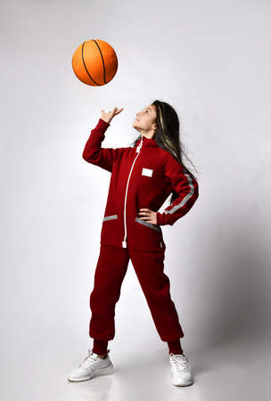 Caucasian preteen girl model in fashion tracksuit playing with basketball ballの写真素材