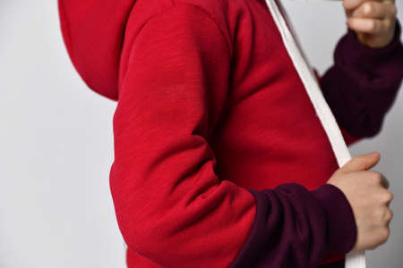 Child in sportive suit put on hood standing back cropped shotの写真素材