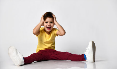 boy in summer t-shirt and shorts sitting on floor studio shotの写真素材