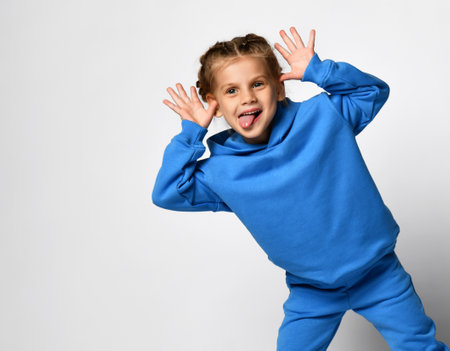 Funny active little girl dressed in sportswear having fun on a white background.の写真素材