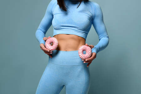 Picture of strong fat woman kicking soft drink and fast food. Shot with yellow background