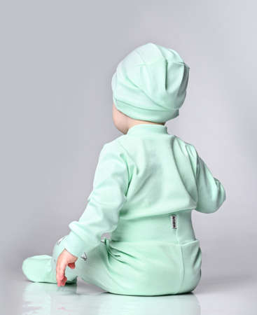 kid baby in cozy cotton body sits back to the cameraの写真素材