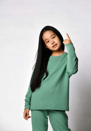 Asian preteen girl pointing finger up advertising good offerの写真素材