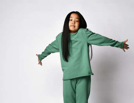 Cute asian preteen girl in green clothing showing dont know gesture