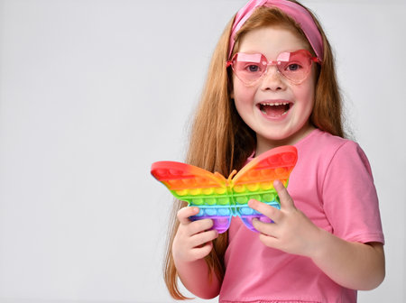 Smiling little red-haired girl child playing with  toy studio shotの写真素材