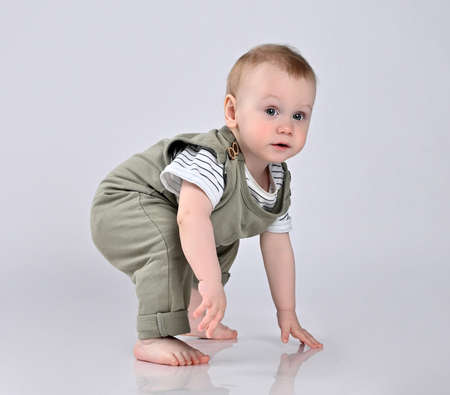 Happy child is sitting on floor, isolated over white