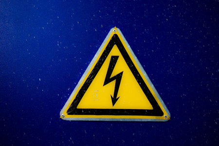 Yellow Electricity Danger Sign on a blue door of high voltage special system.の写真素材
