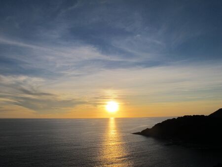                Sunset at sea with a cape sticking out into the sea at the right hand side         の写真素材