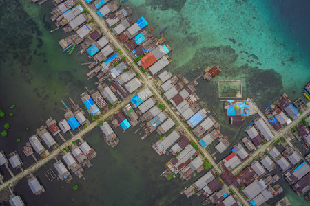 Aerial perspective of a vibrant stilt village over water near a thriving coral reef ecosystem.の写真素材