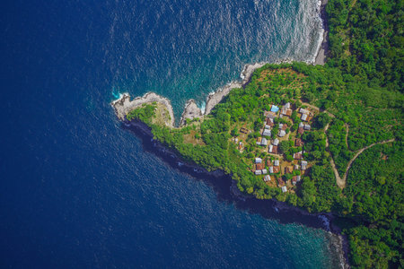 Aerial view of a cliffside village, enveloped in lush greenery, with dramatic ocean views.の写真素材