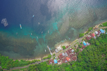 Aerial view of a coastal settlement bordered by clear blue waters and coral reefs, highlighting...