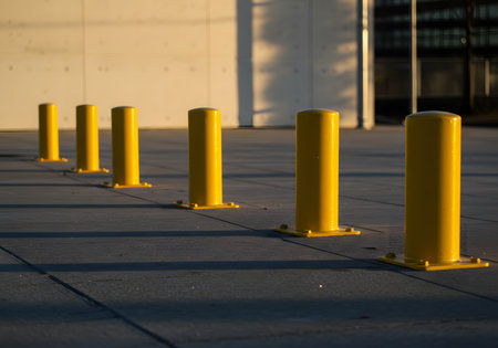 A row of yellow bollards standing on a paved surface under daylight