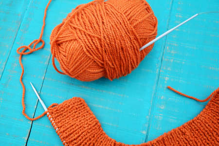 knitting needles and orange yarn on blue backgroundの写真素材