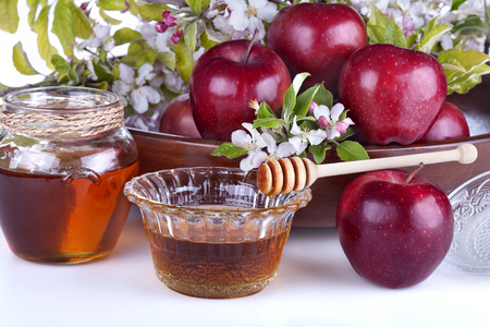 
apples in a bowl with honey and apple flower on a white backgroundの写真素材