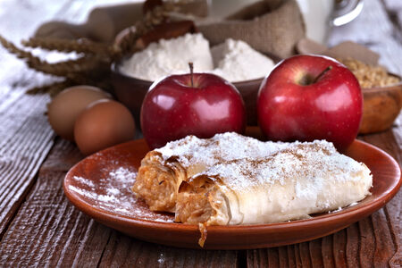 
apple pie on a wooden table with flour and grain in the backgroundの写真素材