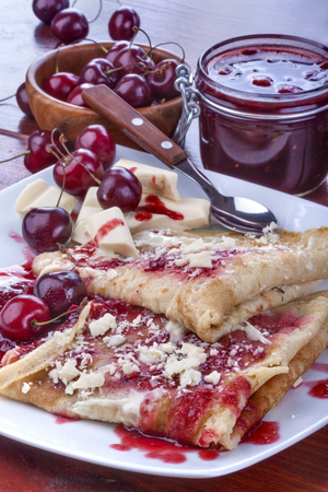 pancakes with jam and cherries topped with white chocolateの写真素材
