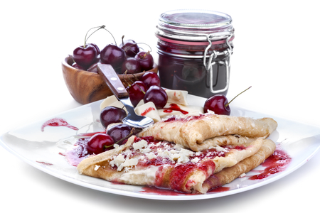 pancakes with jam and cherries topped with white chocolateの写真素材