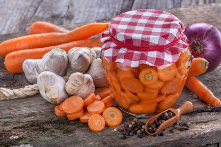 Healthy domestic carrot canned in a jar and on the old rustic tableの写真素材