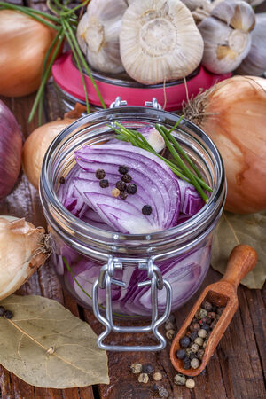 Domestic red onion preserved in jar, with onion and garlic on tableの写真素材