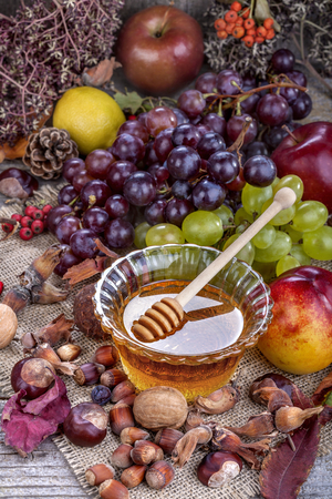 Autumn fruits, nuts and vegetables with honey on the tableの写真素材