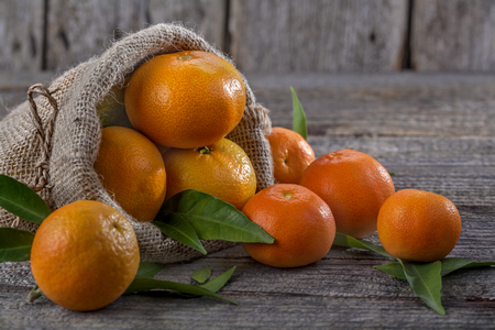 Mandarins in linen bag on a wooden baseの写真素材