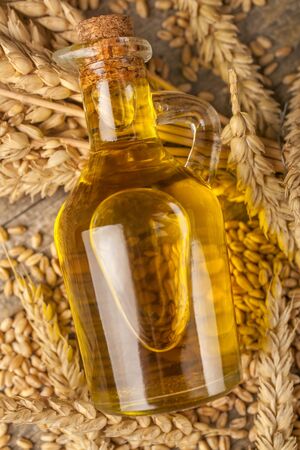 Homemade organically produced wheat oil on a rustic wooden tableの写真素材