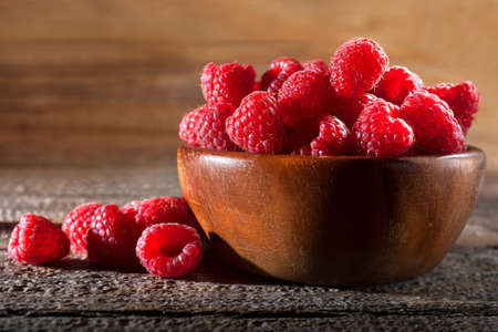 Fresh raspberry in wooden bowl. Close up red raspberries fruit. The concept of healthy eating and...