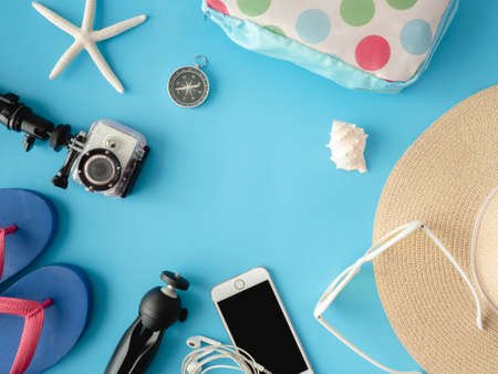 top view travel concept with action camera, map, passport, smartphone and Straw Hat on blue background with copy space, Tourist essentials, vintage tone effectの写真素材