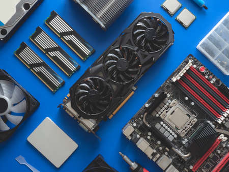 top view of computer parts with harddisk, ram, CPU, graphics card, and motherboard on blue table...