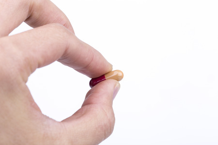 Orange pill in hand on the white background