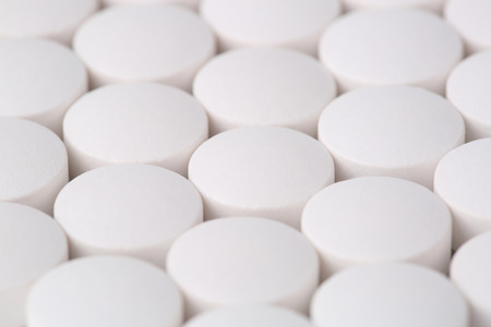 Round white pills closeup sit on a table.の写真素材