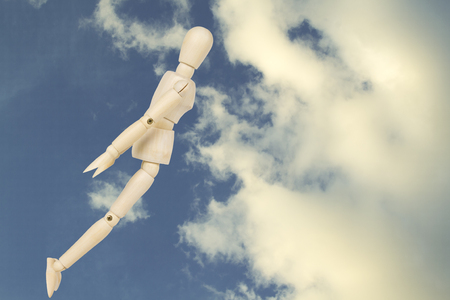 Flying man, man falling down on sky background.wooden figure conceptの写真素材