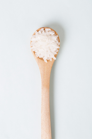Rice grains in a wooden spoon on a blue background.の写真素材