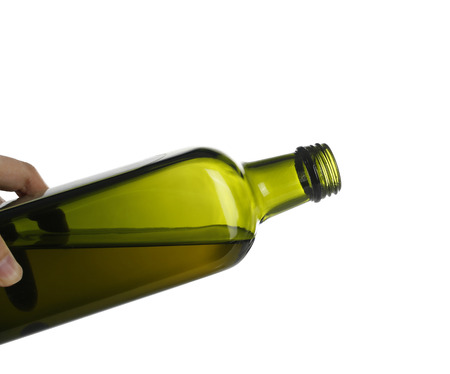 Pouring olive oil from glass bottle against white background.の写真素材