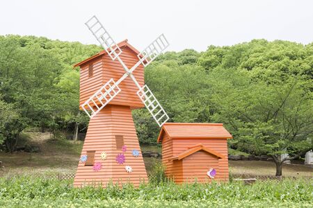 Red windmill in forest park in springtime.の写真素材