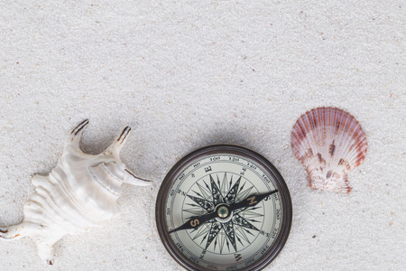 Adventure decoration with compass, shell and conch on the white sand. Abstract background.の写真素材