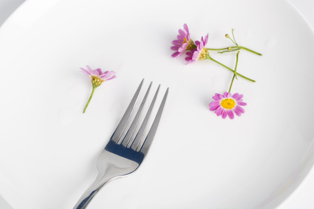 Fork and daisy in a white plate.の写真素材