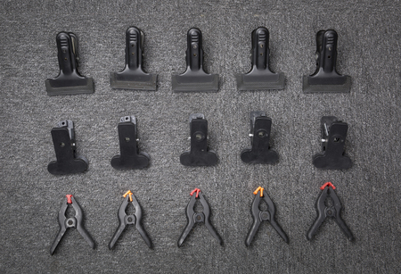 Group of black big clips on the carpet. Top view.