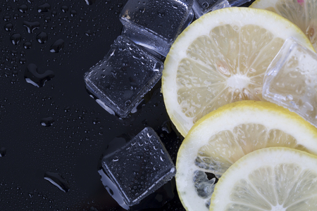 Ice cubes and fresh lemon slices on the black background.の写真素材