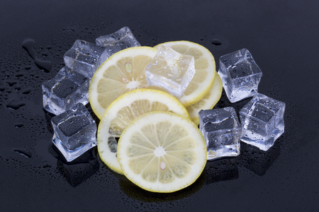 Ice cubes and fresh lemon slices on the black background.の写真素材