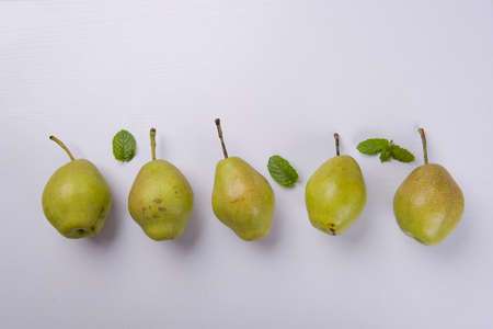 Fresh pears with mint leaves on a white table.の写真素材