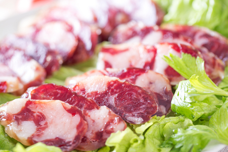 Close-up of cold cuts and vegetables on a plate. Raw pork sausage.の写真素材