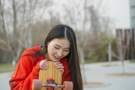 Young skateboard girl holding her longboard outdoors.の写真素材