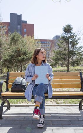 Young woman holding book on benchの写真素材