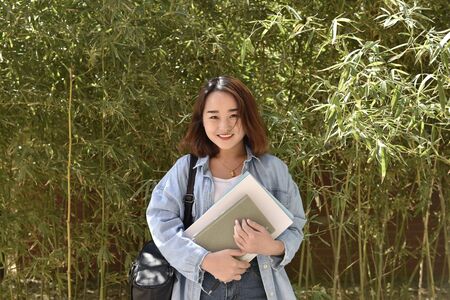 A beautiful college student carrying books at the campus.の写真素材